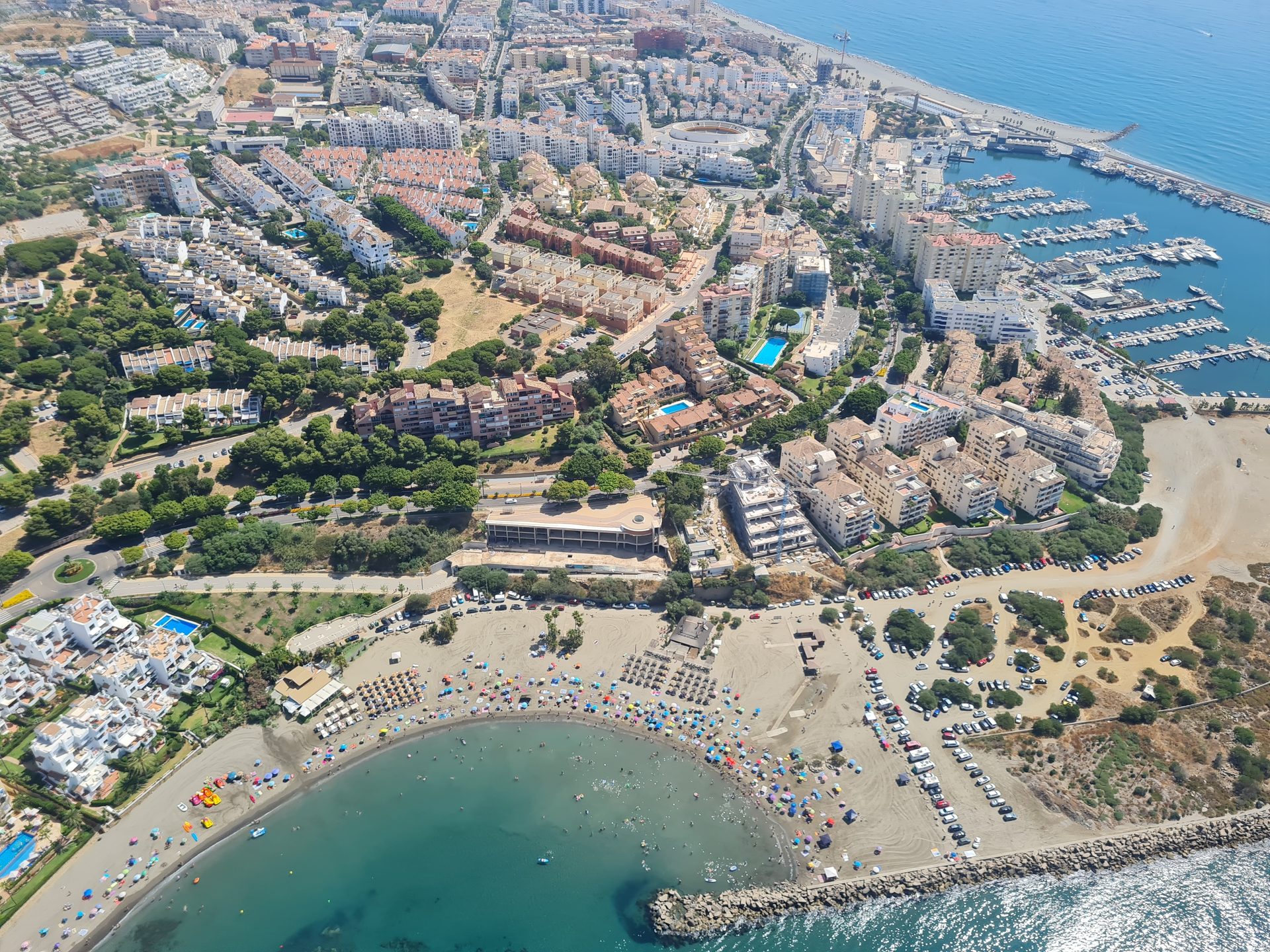 Aerial view of a coastal resort with a private beach, pool, and marina.